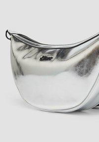 Silberne metallische Handtasche mit geschwungener Form, glatter Textur und schwarzem Reißverschluss. Verfügt über ein prägiertes Logo auf der Vorderseite.