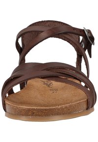 Sandalo in pelle marrone con multiple cinghie incrociate, suola piatta e fibbia laterale regolabile. Sottopiede texturizzato e colore naturale.