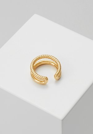 Gold-toned open ring with two twisted rope design bands connected at the ends, displayed on a white square pedestal.