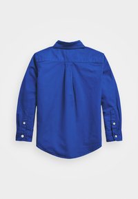 Langarmhemd aus festem blauen Baumwollstoff, mit spitzem Kragen, geknöpften Manschetten und abgerundetem Saum. Rückenfalte für mehr Bewegungsfreiheit.