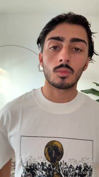 Biała koszulka z nadrukiem graficznym dużej piłki nad tłumem, w kolorach czarnym i żółtym. Gładka, bawełniana faktura.