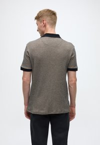 Pelēks polo krekls ar teksturētu rakstu, īsām piedurknēm un tumši zilu apkakli. Aizmugure ir vienkārša, tīra dizaina bez rotājumiem.