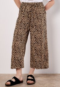 Pantalons large à imprimé léopard avec une taille élastique, deux poches latérales et un tissu doux et léger. Associés à des sandales noires à enfiler.