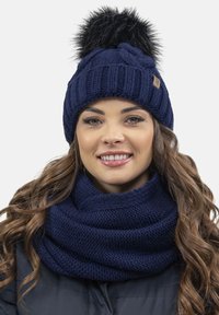 Granatowa, dziana czapka typu beanie z czarnym futrzanym pom-pomem oraz dopasowanym, grubym, dzianym szalikiem w formie infinity, z texturem prążkowanym i metką z logo.