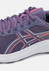 Baskets de course violettes avec une tige en mesh respirant, des accents contrastants en orange et blanc, un système de laçage et une semelle texturée blanche.