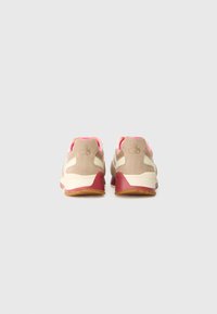 Beige og rosa treningsko med overdel i semsket skinn, hvite sidepaneler og en maroon hæl. Har en teksturert såle for grep.