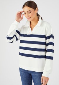 Suéter blanco con rayas horizontales en azul marino y azul claro, con cuello tipo polo y mangas largas. Tejido suave con un corte holgado.