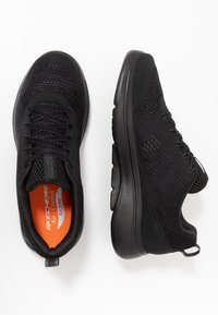 Schwarze Sportschuhe mit einem Obermaterial aus Mesh, strukturierten Akzenten und einer gepolsterten Sohle. Mit Schnürsenkeln und orangefarbener Innenseite.