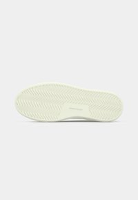 Shoe sole with wavy tread pattern and rectangular area in center embossed with "JACK & JONES" text, in off-white color.