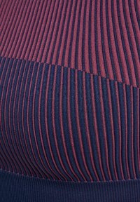 Nahaufnahme eines gerippten Stoffes mit vertikalen marineblauen und burgunderroten Streifen, die die Struktur und den Farbkontrast in einem Strickmuster zeigen.