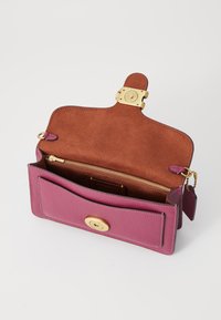 Portefeuille en cuir magenta avec une finition texturée, quincaillerie dorée, intérieur en daim marron et un compartiment zippé. L'avant présente une fermeture à pression.