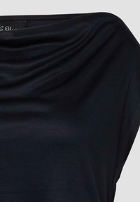 Top nero drappeggiato realizzato in tessuto morbido e liscio con vestibilità rilassata. Presenta una scollatura ampia e un design fluente con una leggera lucentezza.