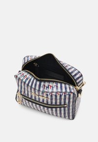 Rektangulær taske lavet af mønstret stof med marineblå og hvide striber, med guld lynlåse, en sort inderside og en logoakse.