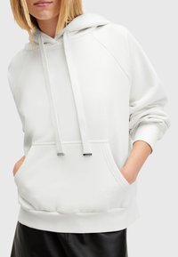 Witte hoodie met een ontspannen pasvorm, voorzien van een buidelzak, geribbelde manchetten en trekkoorden met metalen uiteinden. Glad oppervlak.