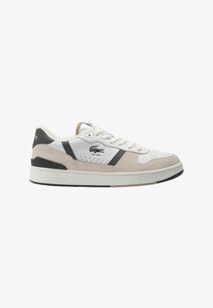 Zapatilla blanca de cuero con acentos de ante gris y beige, puntera perforada, diseño de cordones y una gruesa suela blanca. Logo de Lacoste en el lateral.