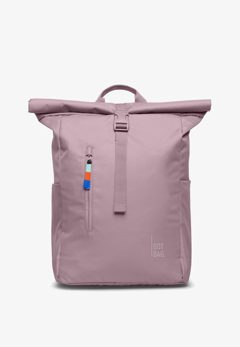 Sac à dos à rabat enroulable violet clair avec poche zippée avant, tirette colorée, poignée supérieure, poches latérales et logo "GOT BAG" en bas à droite sur le devant.