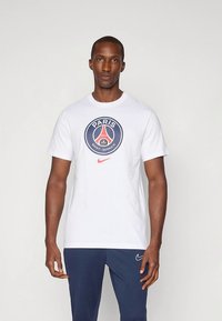 Witte T-shirt met korte mouwen, voorzien van een ronde Paris Saint-Germain-logo in marineblauw en rood, gemaakt van zacht katoen.