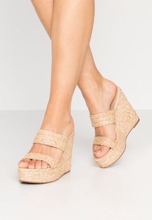 Beige wedge sandalen met geweven textuur, met twee brede banden over de voet en een gestructureerde platformzool.
