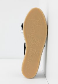 Semelle d'une chaussure pour femme avec le logo "Pretty Ballerinas", semelle en caoutchouc, taille 37, inclinée contre un mur d'angle blanc.