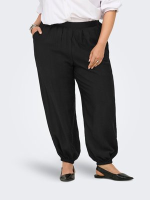 Person, der bære løstsiddende sort bukser med elastiske manchetter, hvid skjorte med opkærmede ærmer, sorte slingback flade sko, sølvur og ring.