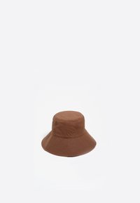 Sombrero de cubo marrón hecho de un material liso y flexible. Presenta un ala ancha que se inclina hacia abajo y una corona redondeada sin acentos visibles.