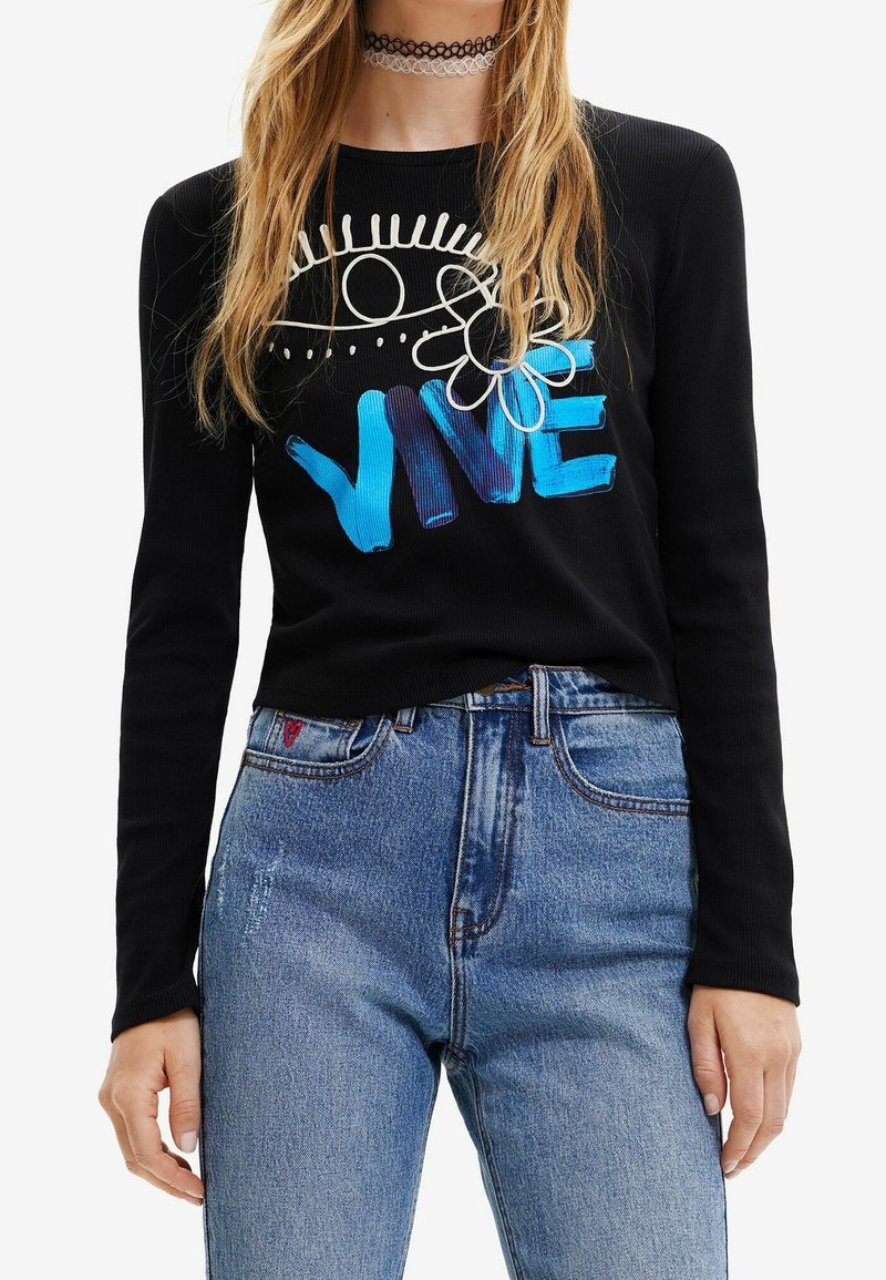 Schwarzes Langarmshirt aus geripptem Stoff. Mit blauer und weißer grafischer Schrift "VIVE" und floraler Gestaltung. Kombiniert mit hoch taillierten blauen Jeans.