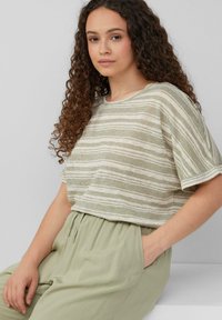 Lichtgroene gestreepte top met korte mouwen in een gestructureerde stof, gecombineerd met losse, lichtgroene broeken met een trekkoord in de taille en zakken.