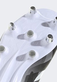 Crna i bijela potplata nogometne kopačke s šest oštrih krampona. Teksturirana bijela površina s geometrijskim uzorcima i srebrnim metalnim akcentima.