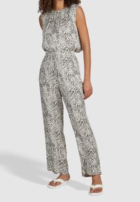 Combinaison imprimé léopard avec haut sans manches, taille élastique et pantalons larges. Confectionnée dans un tissu léger et lisse en tons noir et blanc.