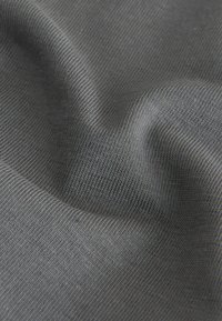 Gros plan sur la texture d'un tissu tricoté côtelé gris avec des points fins visibles et des plis subtils.