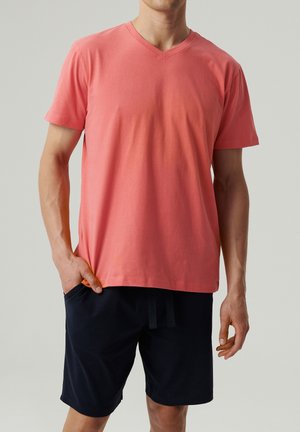 T-shirt z krótkim rękawem w kolorze koralowym, z dekoltem w serek, o luźnym kroju i gładkiej fakturze, zestawiony z granatowymi szortami z kieszeniami.