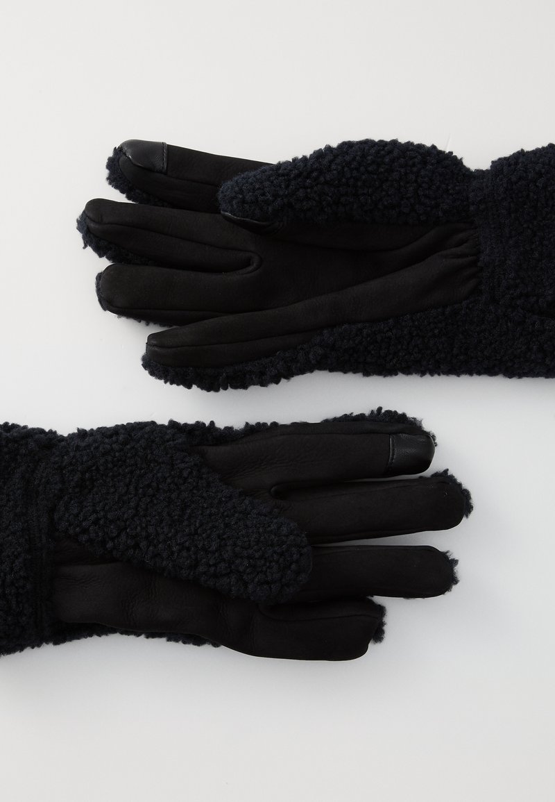 Gants noirs avec un extérieur en polaire texturé et des paumes en cuir lisse. Les poignets ont une finition douce et duveteuse pour plus de chaleur.