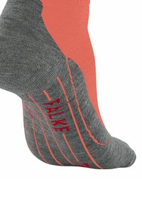 Calcetín gris con acentos en rojo y naranja, que muestra el nombre de la marca "FALKE" y patrones texturizados para agarre y estilo.