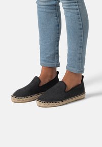 Scarpe slip-on nere realizzate in tessuto testurizzato, con suola in juta intrecciata e lati elasticizzati per una facile calzata. Abbinate a jeans azzurri chiari.