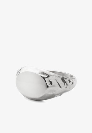 Hopeinen sinettisormus, jossa sileä ovaali pintakuvio ja vasaratyylinen kuvioitu sormi. Valkoisella taustalla.