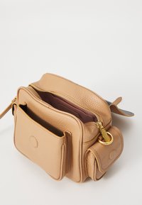 Tan leather crossbody bag with a textured surface, a zippered main compartment, and two front pockets. Gold hardware accents provided.