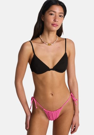 Top bikini a triangolo nero a coste con sottili spalline, abbinato a slip bikini rosa con frange e chiusure a fiocco.