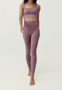Mauve träningsset som består av en åtsittande kortärmad topp med smala band och högmidjade leggings med texturerade sömmar och en slät yta.
