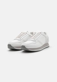 White athletic shoes with a smooth leather upper, light gray accents, and a textured toe cap. Features laces and a cushioned sole.