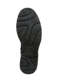 Suela de goma negra con patrones de relieve y ranuras. Presenta una marca en un área rectangular. Talla impresa como 36.