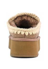 Pantofole in suede marrone con suola piatta color sabbia, dettagli cuciti in crema attorno all'apertura e morbido rivestimento interno peloso.