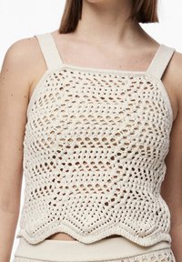 Top sin mangas de ganchillo en color crema, con un patrón de diamantes, tirantes anchos y un dobladillo en forma de concha. Fabricado con hilo texturizado.