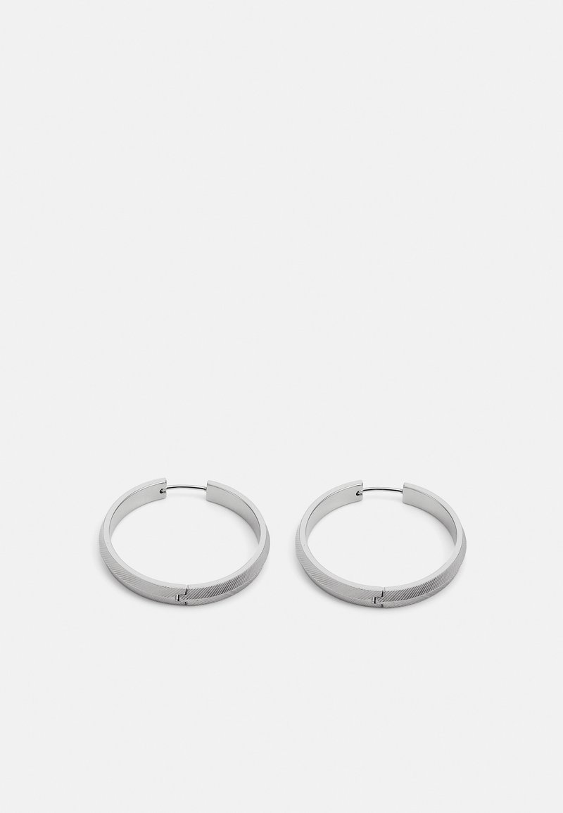 Boucles d'oreilles en argent en forme de cercle avec une finition lisse et texturée, dotées d'un fermoir simple. Forme circulaire avec un aspect légèrement mat.