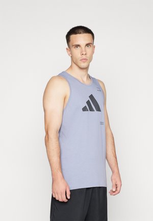 Top fără mâneci de culoare gri, cu logo-ul Adidas negru. Material ușor, guler rotund, croială lejeră și textură fină. Șorturi negre vizibile.