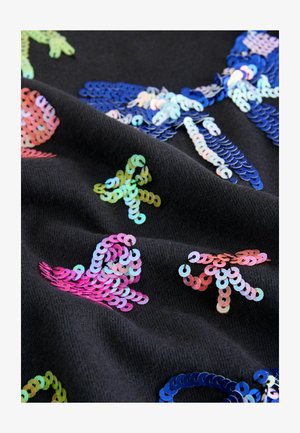 Tessuto nero con paillettes colorate a forma di vita marina, tra cui meduse rosa, stelle marine verdi e pesci blu, che mostrano una superficie lucida.