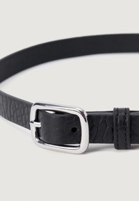 Schwarzer Ledergürtel mit strukturierter Oberfläche, ausgestattet mit einer glänzenden silbernen Metallschnalle und einer kleinen Schlaufe zur Verstellung.