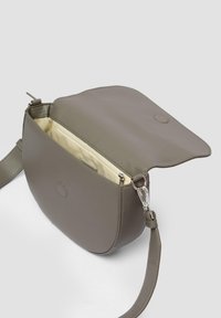 Graue Leder-Crossbody-Tasche mit runder Form, magnetischem Verschluss und Innentasche. Mit abnehmbarem Tragegurt und glatter Textur.