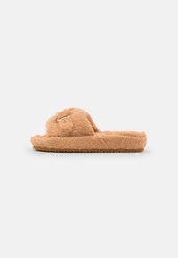Fuzzy brown slipper with a thick sole, wide band, metallic buckle detail, and plush texture, designed for comfort and warmth.