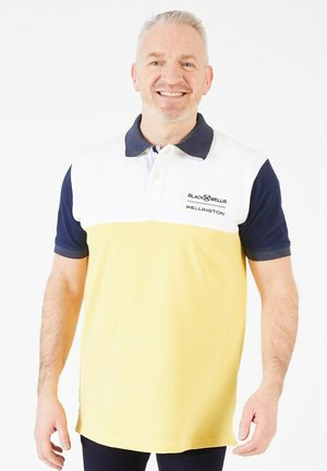 Un polo à manches courtes avec un bas jaune, un devant blanc et des manches bleu marine. Détails de logo brodés sur le côté gauche. En matière de coton.