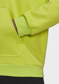 Neongrüner Kapuzenpullover mit Kängurutasche, gerippten Bündchen und Saum. Weicher Stoff mit nahtlosem Design und ohne sichtbare Hardwaredetails.